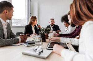 gens qui sont assis autour d'une table pour participer à une réunion d'entreprise