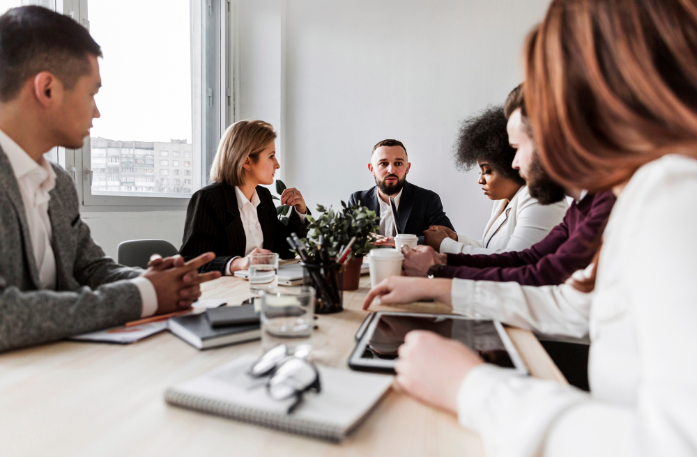 gens qui sont assis autour d'une table pour participer à une réunion d'entreprise